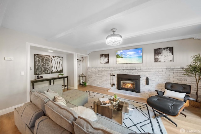 living room with light hardwood / wood-style flooring, beamed ceiling, brick wall, and a brick fireplace