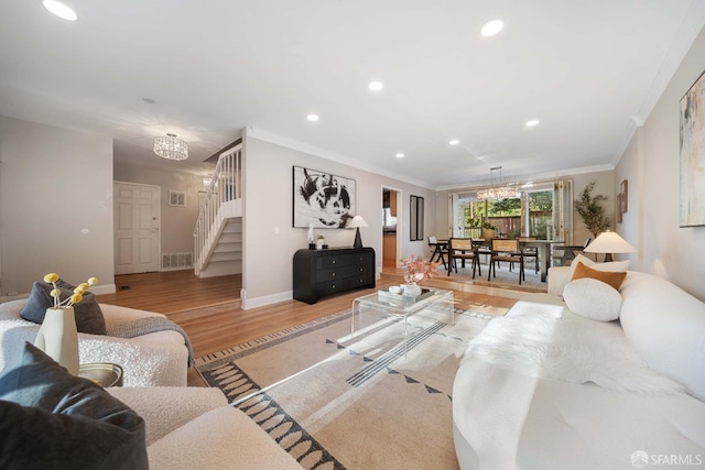 living room with a chandelier, ornamental molding, and light hardwood / wood-style floors