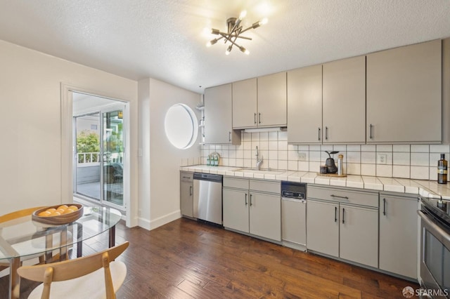 kitchen featuring appliances with stainless steel finishes, a sink, decorative backsplash, and dark wood-style floors