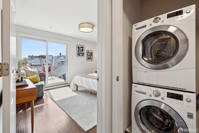 laundry room with laundry area, wood finished floors, and stacked washer and clothes dryer