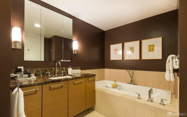 bathroom featuring a relaxing tiled tub and vanity