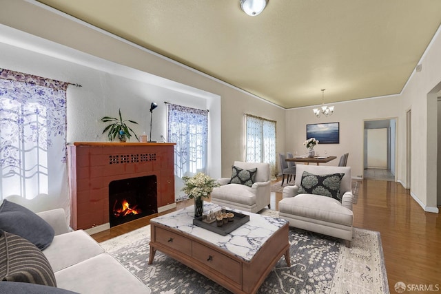 living room with a tile fireplace, wood finished floors, a notable chandelier, and baseboards