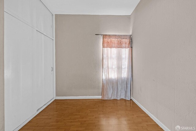 spare room featuring wood finished floors and baseboards
