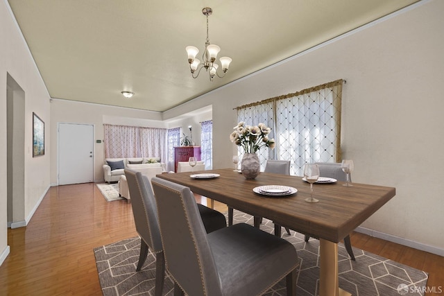 dining space featuring baseboards, light wood-style floors, and a notable chandelier