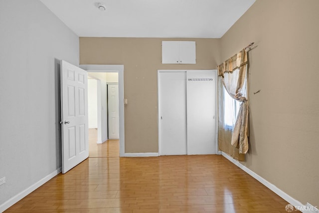 unfurnished bedroom featuring baseboards, light wood-style floors, and a closet