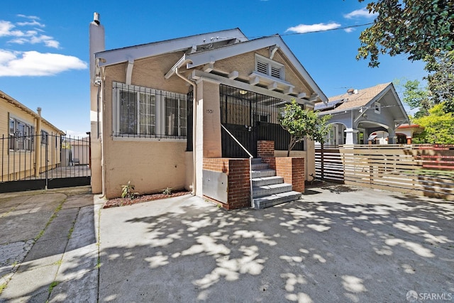 bungalow-style house with fence, a chimney, and stucco siding
