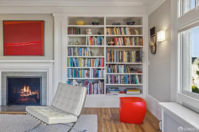 living area with radiator, built in features, and light hardwood / wood-style flooring