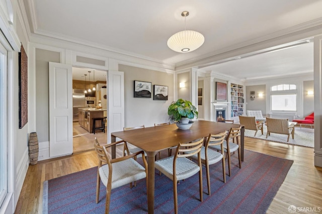 dining space with ornamental molding and light hardwood / wood-style floors