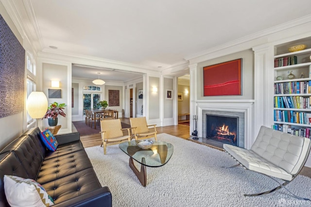 living room featuring built in shelves, wood-type flooring, and ornamental molding