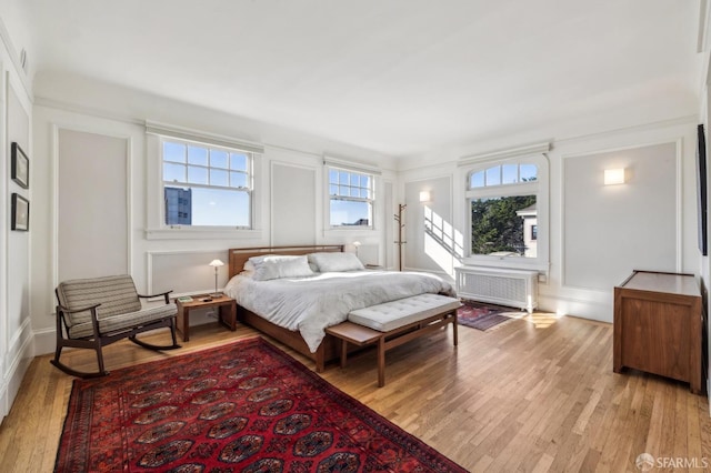 bedroom featuring radiator heating unit and light hardwood / wood-style floors