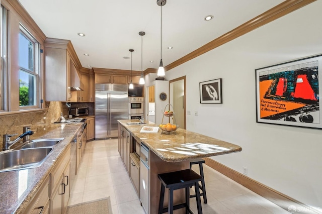 kitchen with appliances with stainless steel finishes, sink, backsplash, hanging light fixtures, and a kitchen island with sink