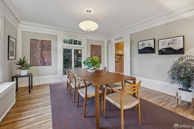 dining area with crown molding, radiator heating unit, and light hardwood / wood-style flooring