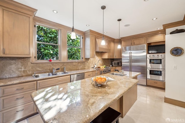 kitchen featuring a kitchen island with sink, sink, light stone counters, and stainless steel appliances