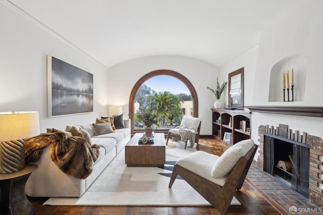 living room with a brick fireplace, vaulted ceiling, and parquet floors