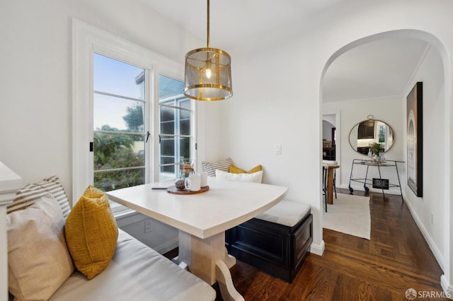 dining space featuring breakfast area and dark parquet flooring