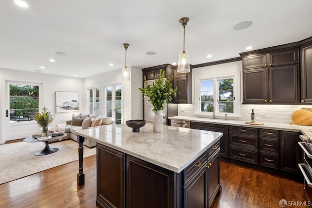 kitchen featuring pendant lighting, dark hardwood / wood-style floors, a center island, and dark brown cabinets