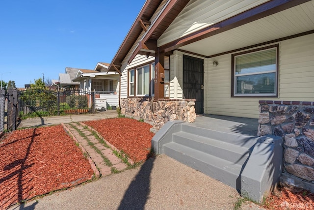 property entrance featuring stone siding, fence, and a porch