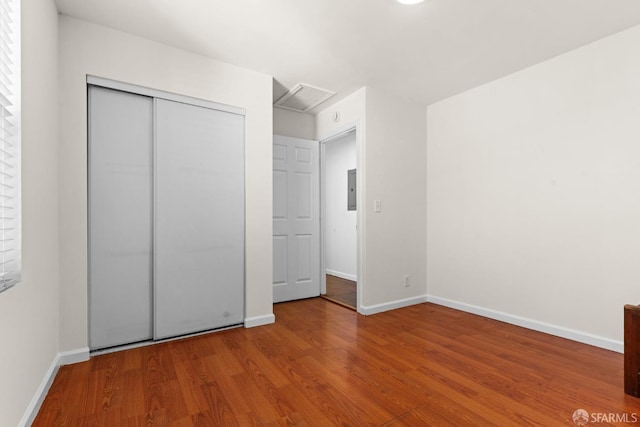 unfurnished bedroom featuring attic access, a closet, baseboards, and wood finished floors