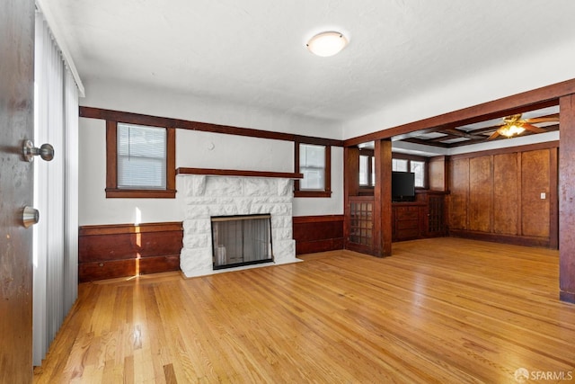 unfurnished living room featuring a wainscoted wall, a fireplace, wood finished floors, and wooden walls