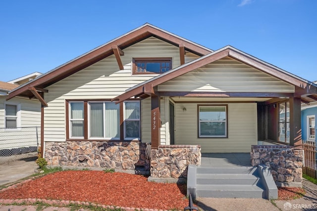 view of front of home with crawl space, stone siding, and a porch