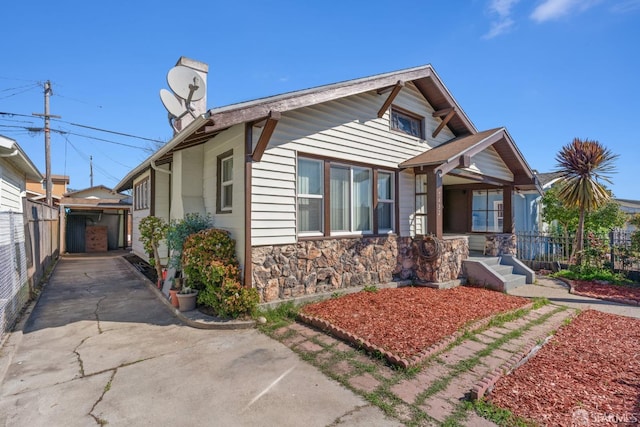 view of front of property featuring stone siding and fence