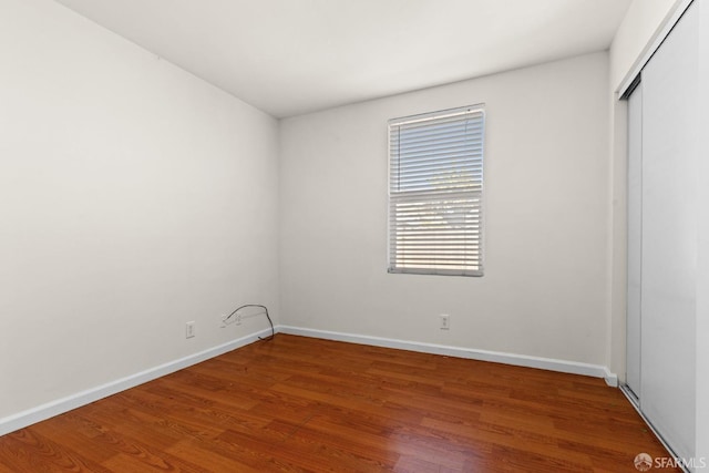 unfurnished bedroom with a closet, baseboards, and wood finished floors