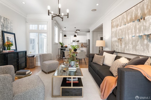 living room featuring crown molding, an inviting chandelier, and light hardwood / wood-style floors