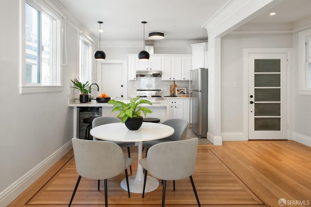 dining room featuring wine cooler, ornamental molding, and light hardwood / wood-style floors