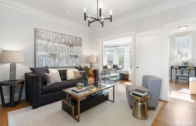 living room with an inviting chandelier, ornamental molding, and light wood-type flooring