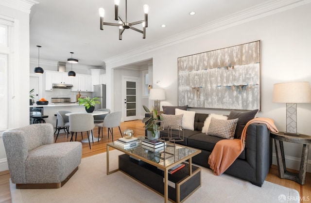 living room featuring ornamental molding, a chandelier, and light hardwood / wood-style floors