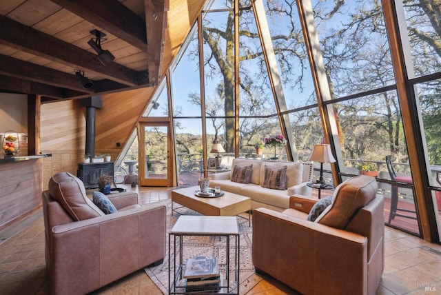 living room featuring a wood stove, floor to ceiling windows, wood ceiling, wood walls, and beamed ceiling