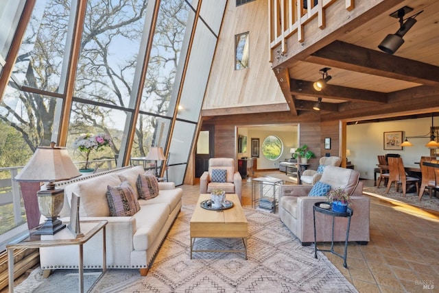living area featuring beamed ceiling, wood ceiling, wood walls, and a towering ceiling