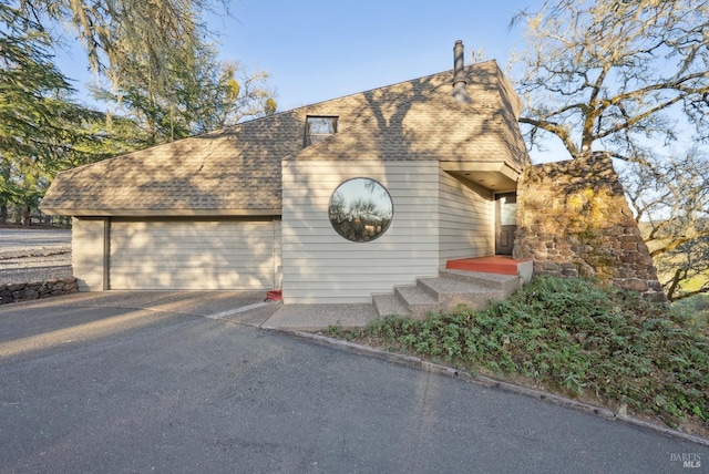 view of front of house featuring a garage and a shingled roof