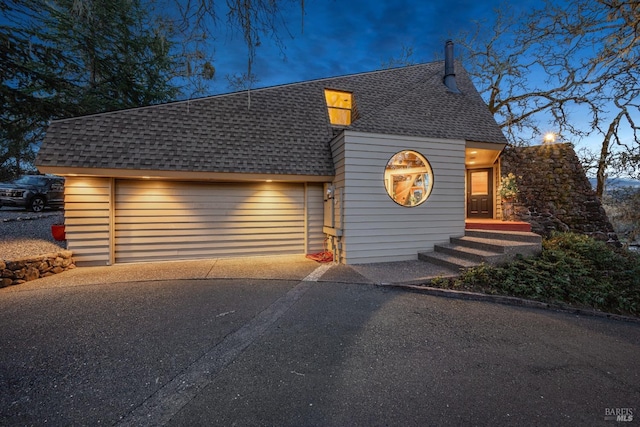 view of front of property with aphalt driveway, an attached garage, and a shingled roof