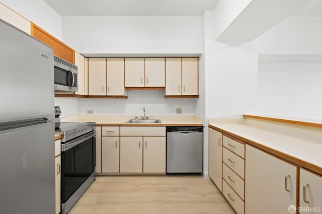 6363 Christie Ave Unit 1823, Emeryville, CA 94608 - kitchen with light wood-type flooring, light countertops, cream cabinetry, a sink, and stainless steel appliances