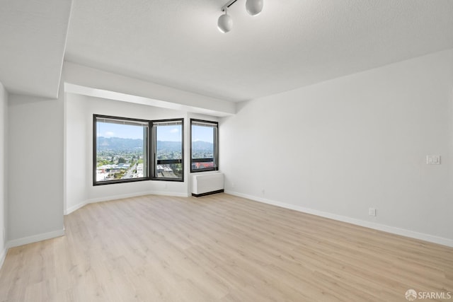 6363 Christie Ave Unit 1823, Emeryville, CA 94608 - empty room featuring light wood-type flooring, a textured ceiling, and baseboards