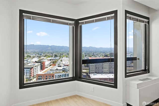 6363 Christie Ave Unit 1823, Emeryville, CA 94608 - spare room featuring a view of city, baseboards, a mountain view, and wood finished floors