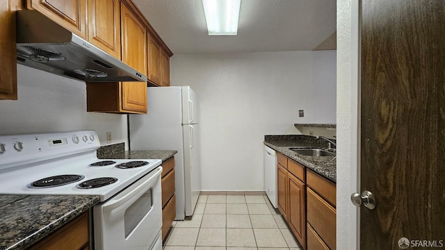 kitchen with dark stone countertops, sink, light tile patterned floors, and white appliances