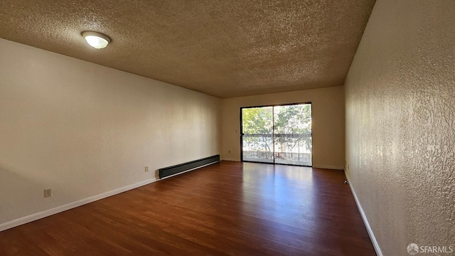 spare room featuring a baseboard radiator, dark hardwood / wood-style floors, and a textured ceiling