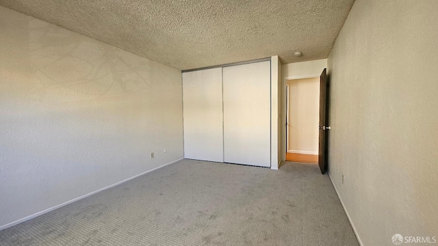 unfurnished bedroom featuring light colored carpet, a closet, and a textured ceiling