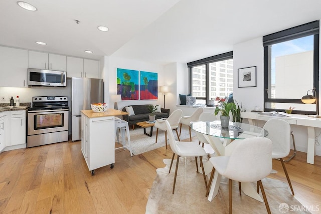 kitchen with wood counters, light hardwood / wood-style flooring, appliances with stainless steel finishes, a kitchen island, and white cabinets