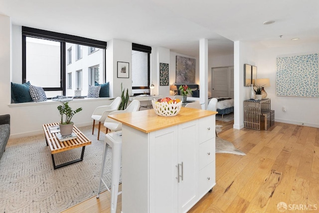 kitchen featuring white cabinetry, a kitchen bar, a center island, and light hardwood / wood-style flooring