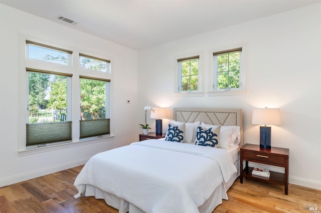 bedroom with visible vents, baseboards, and wood finished floors