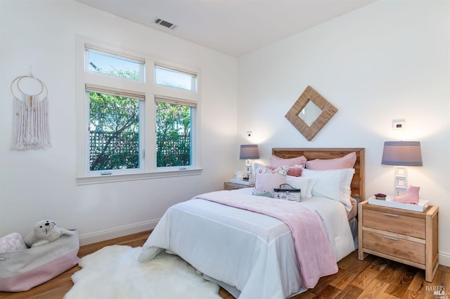 bedroom with wood finished floors, visible vents, and baseboards