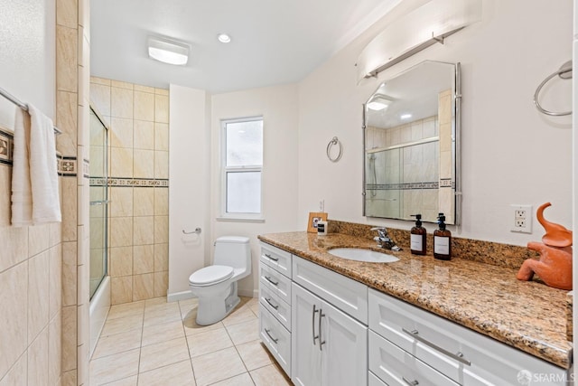 bathroom featuring tile patterned floors, toilet, combined bath / shower with glass door, and vanity