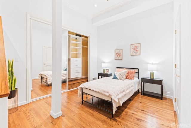 bedroom featuring light wood-style floors, baseboards, and ornamental molding