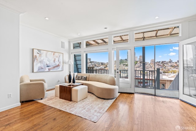 living area with a city view, baseboards, ornamental molding, recessed lighting, and wood finished floors