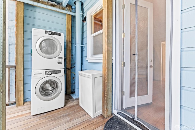 clothes washing area with stacked washer and dryer, light wood-style floors, and laundry area