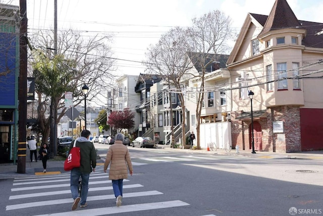 view of road featuring street lighting, sidewalks, a residential view, and curbs