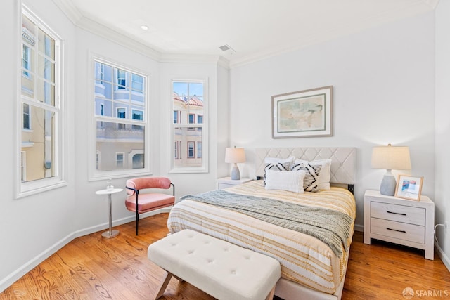 bedroom featuring crown molding, light wood finished floors, baseboards, and visible vents